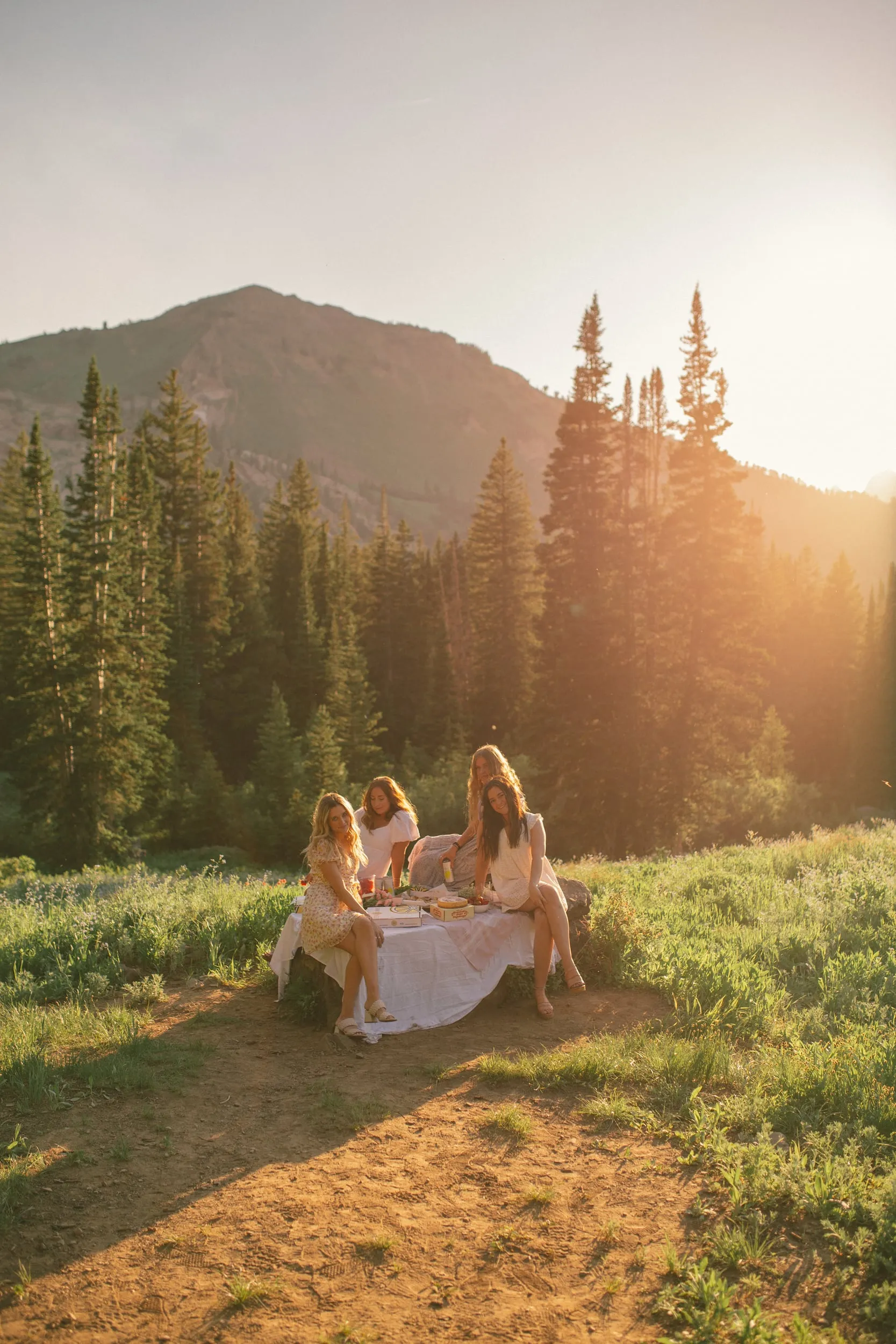 Three friends at a sunset picnic in a mountain meadow above American Fork